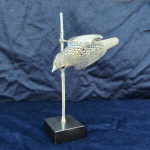 Rousserolle argenté de la collection Lumière d’argent créée par Christofle entre 1987 et 1994 dans sa manufacture de Saint-Denis. L'oiseau est agrémenté d’yeux en onyx. Oiseau agrippé sur une baguette représentant un bambou. Le tout fixé sur un socle lesté noir. Magnifique travail de ciselure, ressemble à de la dentelle. Très bon état. Hauteur : 19,5 cm