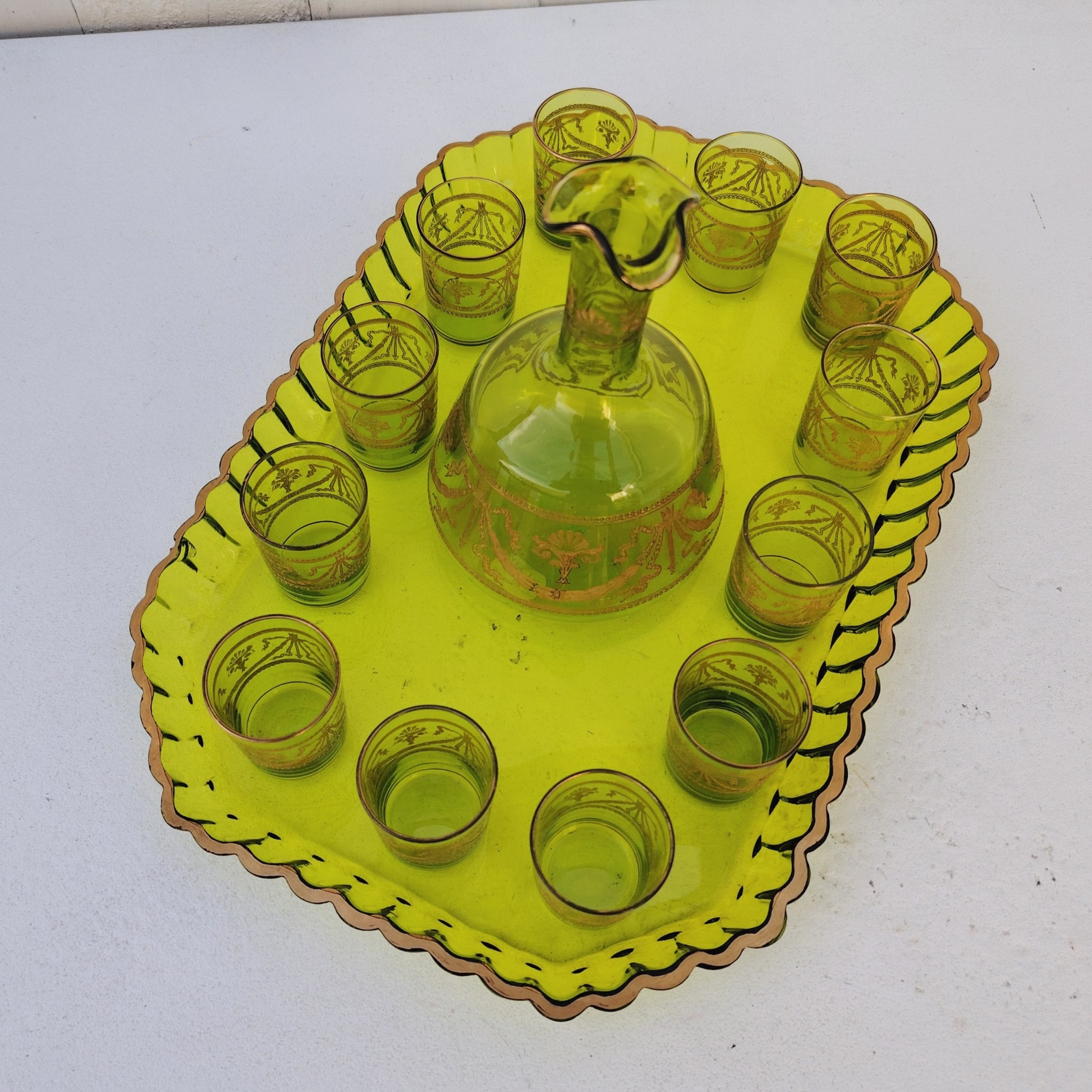 Service à liqueur en cristal de Saint Louis . Le service est composé de 12 verres à liqueur, d'une carafe et d'un plateau. Cristal teinté vert avec dorure. Non estampillé car datant d'avant 1936. Petites rayures d'usage. Manque certainement le bouchon de la carafe. Une paillette sur le rebord du plateau Bon état général. Dimension plateau : 30,5 cm x 21 cm Hauteur verre : 5 cm Diamètre verre : 3,5 cm Hauteur Carafe : 14,5 cm