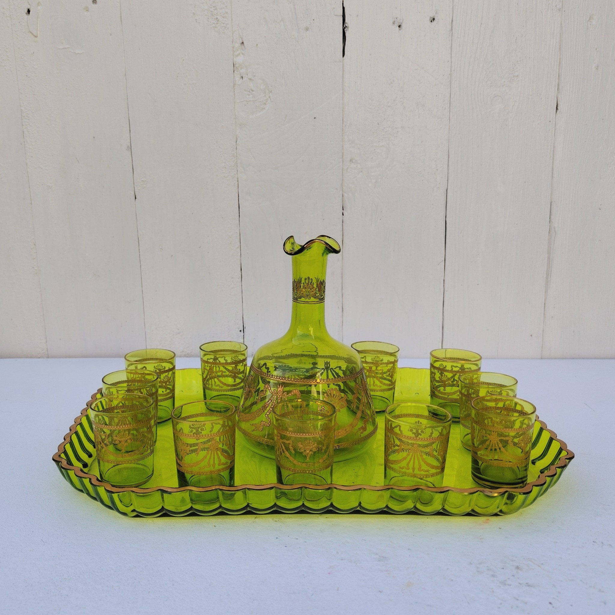 Service à liqueur en cristal de Saint Louis . Le service est composé de 12 verres à liqueur, d'une carafe et d'un plateau. Cristal teinté vert avec dorure. Non estampillé car datant d'avant 1936. Petites rayures d'usage. Manque certainement le bouchon de la carafe. Une paillette sur le rebord du plateau Bon état général. Dimension plateau : 30,5 cm x 21 cm Hauteur verre : 5 cm Diamètre verre : 3,5 cm Hauteur Carafe : 14,5 cm