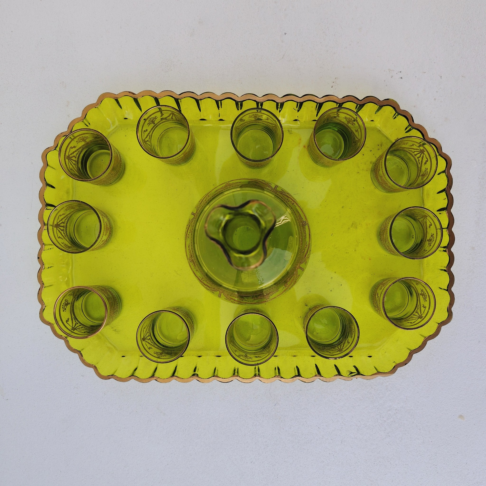 Service à liqueur en cristal de Saint Louis . Le service est composé de 12 verres à liqueur, d'une carafe et d'un plateau. Cristal teinté vert avec dorure. Non estampillé car datant d'avant 1936. Petites rayures d'usage. Manque certainement le bouchon de la carafe. Une paillette sur le rebord du plateau Bon état général. Dimension plateau : 30,5 cm x 21 cm Hauteur verre : 5 cm Diamètre verre : 3,5 cm Hauteur Carafe : 14,5 cm