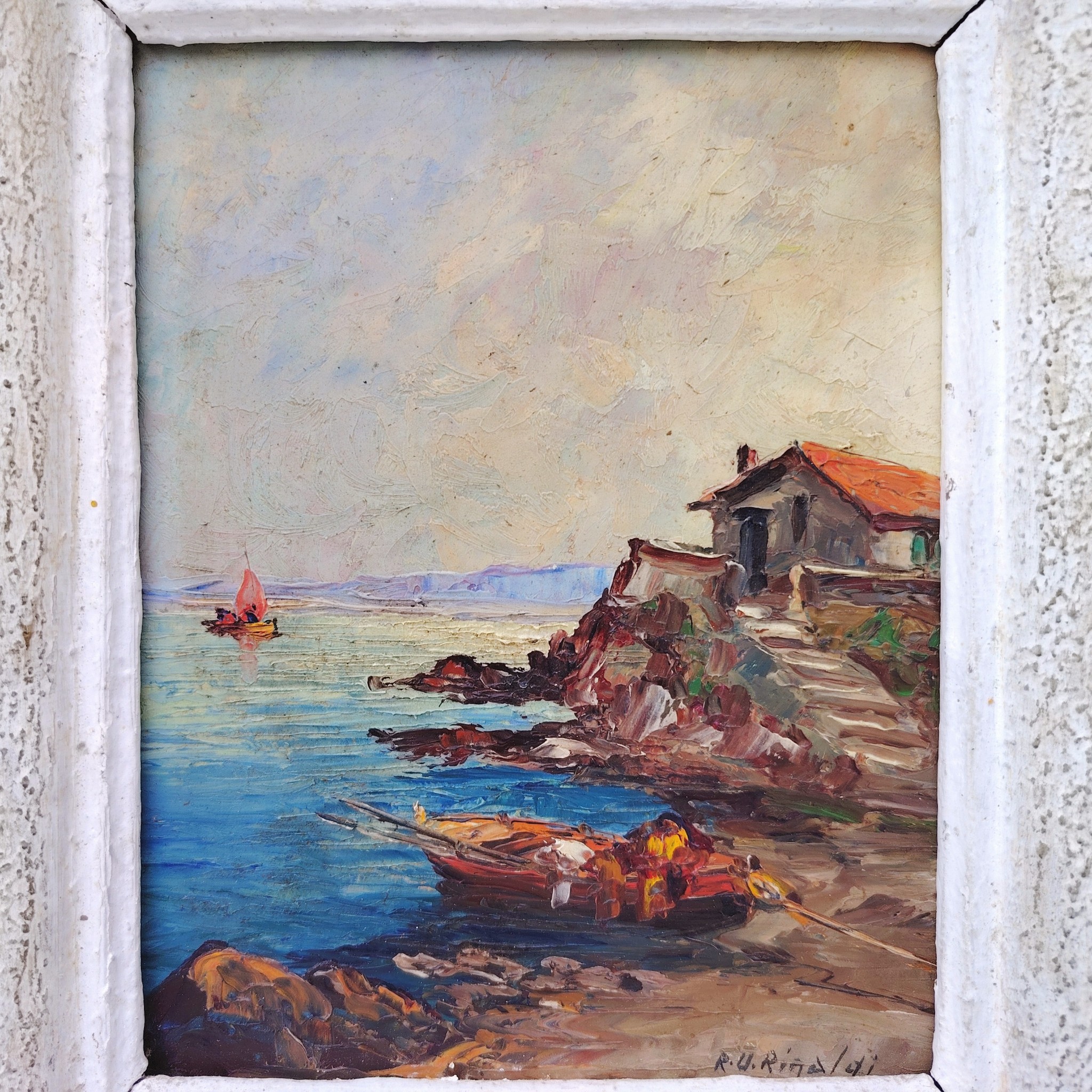Huile sur panneau isorel représentant un bateau amarré dans une crique en premier plan , en deuxième plan une maison de pêcheur sur une hauteur et dans le fond on distingue une falaise et un voilier naviguant. Cadre en bois cérusé blanc. Signé RU Rinaldi en bas à droite. Bon état général. Dimensions cadre : 22 x 25,5 cm