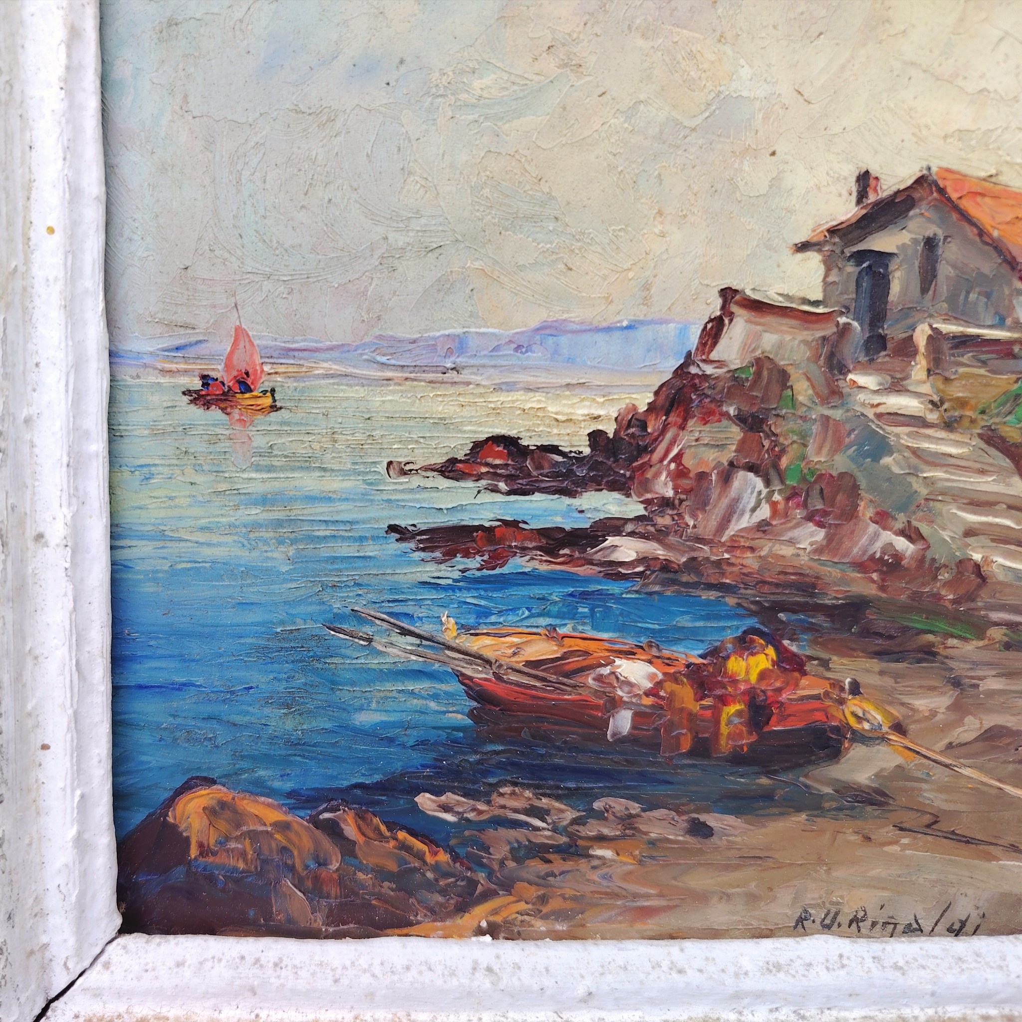 Huile sur panneau isorel représentant un bateau amarré dans une crique en premier plan , en deuxième plan une maison de pêcheur sur une hauteur et dans le fond on distingue une falaise et un voilier naviguant. Cadre en bois cérusé blanc. Signé RU Rinaldi en bas à droite. Bon état général. Dimensions cadre : 22 x 25,5 cm