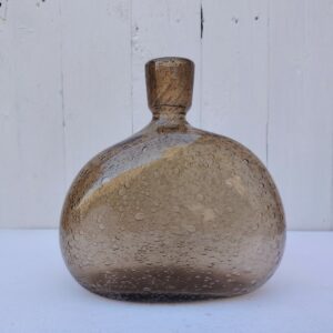 Bouteille en verre épais bullé, dans les tons ambré/fumé. Un bout d'étiquette " Verrerie de Bendor" sur le bas de la bouteille Excellent état. Hauteur : 20 cm Largeur : 19 cm