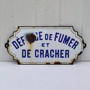 Plaque émaillée bombée " Défense de fumer et de cracher" datant des années 50-60. Deux points d'accroche sur les cotés. Des éclats sur le contour et un gros éclat sur le mot Défense. Le gros éclat est certainement dû aux enfants des années 50-60 qui faisait éclater l'émail des plaques à coup de lance pierre, un vrai sport national . Dimensions : 34,5 x 16 cm
