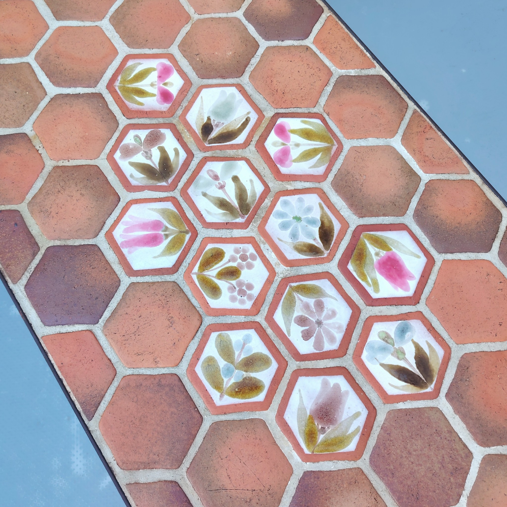 Table basse par Roger Capron à Vallauris. Piétement en métal noir, plateau en tomettes provençales et céramique à fleur. Modèle peu commun. Signé sur la table . Quelques traces et rayures d'usage. Très bon état. Hauteur : 39 cm dimensions plateau : 82,5 x 39,5 cm