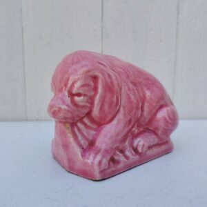 Ancienne tirelire a casser représentant un chien, en faïence d'Onnaing. De couleur rose. Numérotée sur le dessous. Trois féles au niveau de la fente. Bon état Dimensions : 7,5 x 11 x 5,5 cm