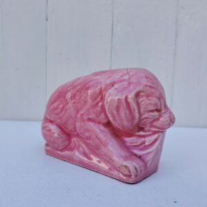 Ancienne tirelire a casser représentant un chien, en faïence d'Onnaing. De couleur rose. Numérotée sur le dessous. Trois féles au niveau de la fente. Bon état Dimensions : 7,5 x 11 x 5,5 cm