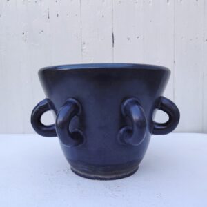 Cache pot à multi anses en céramique noire irisée d'Accolay. Signé sur le dessous Accolay. Des éclat sur le bas. Un trou a été percé dans le fond pour éviter la stagnation de l'eau. Traces d'usage à l'intérieur. Bon état général. Hauteur : 18,5 cm Diamètre extérieur : 24 cm Diamètre intérieur : 21 cm