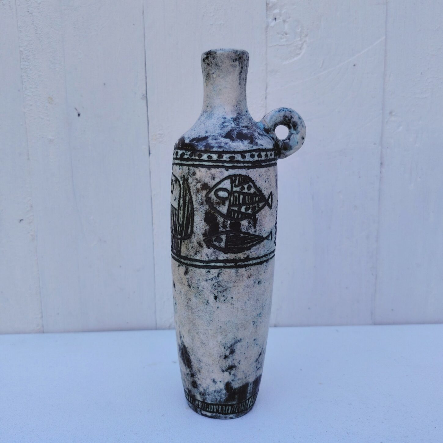 Vase soliflore en forme d'amphore en céramique dans les tons gris, créée par Jacques Blin dans la années 60. Décor incisé de poissons et oiseaux. L'anse a été cassée et recollée pas très visible Bon état général Hauteur : 21,5 cm