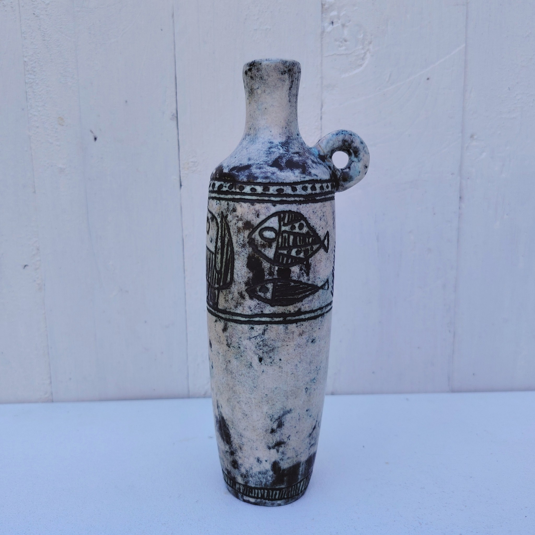 Vase soliflore en forme d'amphore en céramique dans les tons gris, créée par Jacques Blin dans la années 60. Décor incisé de poissons et oiseaux. L'anse a été cassée et recollée pas très visible Bon état général Hauteur : 21,5 cm