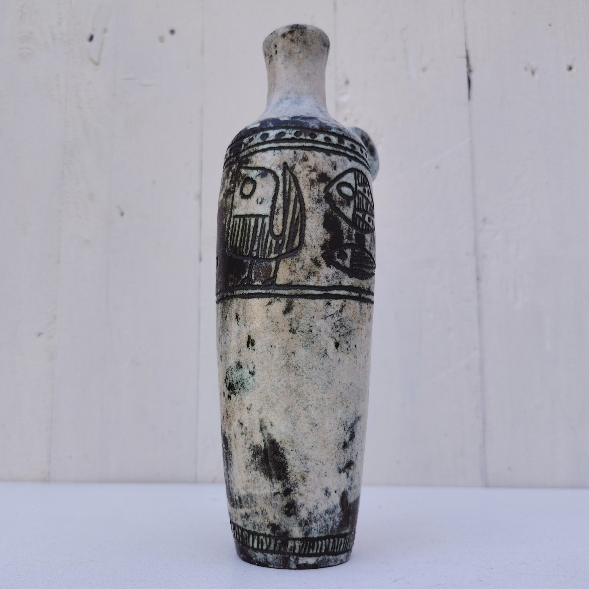 Vase soliflore en forme d'amphore en céramique dans les tons gris, créée par Jacques Blin dans la années 60. Décor incisé de poissons et oiseaux. L'anse a été cassée et recollée pas très visible Bon état général Hauteur : 21,5 cm
