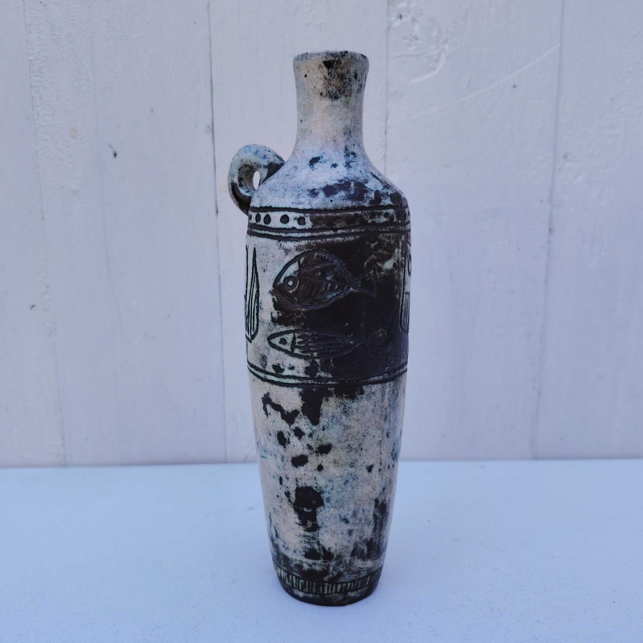 Vase soliflore en forme d'amphore en céramique dans les tons gris, créée par Jacques Blin dans la années 60. Décor incisé de poissons et oiseaux. L'anse a été cassée et recollée pas très visible Bon état général Hauteur : 21,5 cm