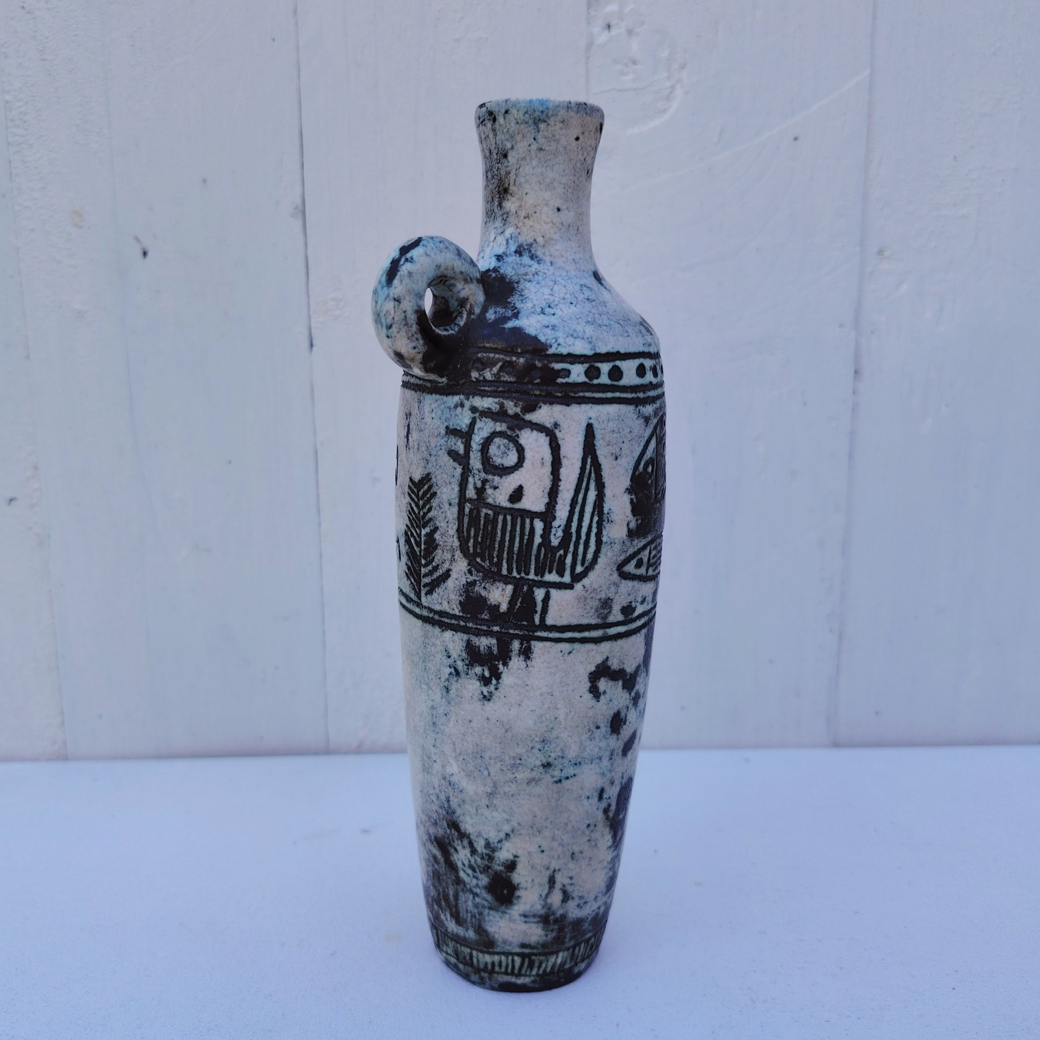 Vase soliflore en forme d'amphore en céramique dans les tons gris, créée par Jacques Blin dans la années 60. Décor incisé de poissons et oiseaux. L'anse a été cassée et recollée pas très visible Bon état général Hauteur : 21,5 cm