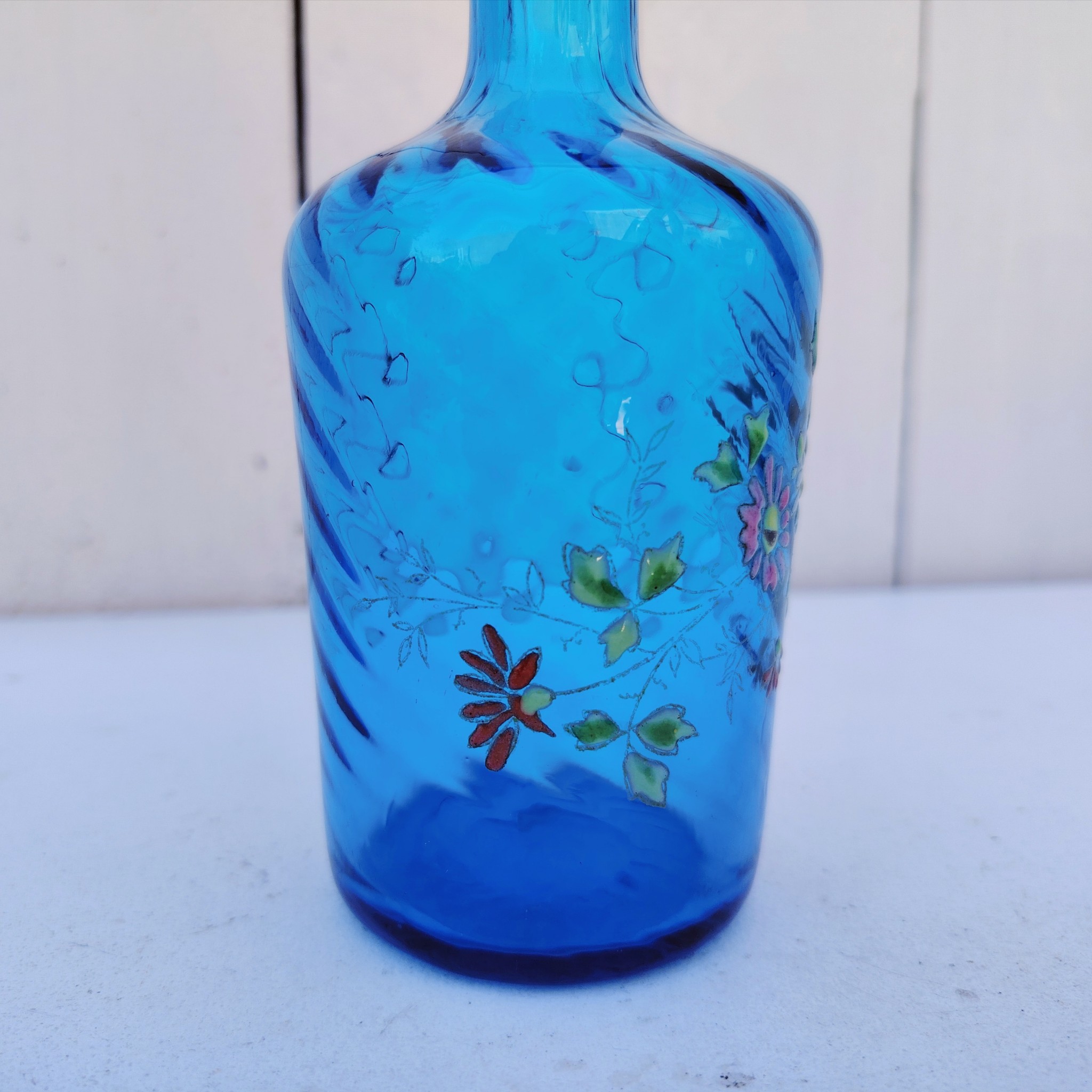 Ancienne bouteille en verre  torsadé de couleur bleu à décor frise florale émaillée Très bon état. Hauteur  : 17 cm