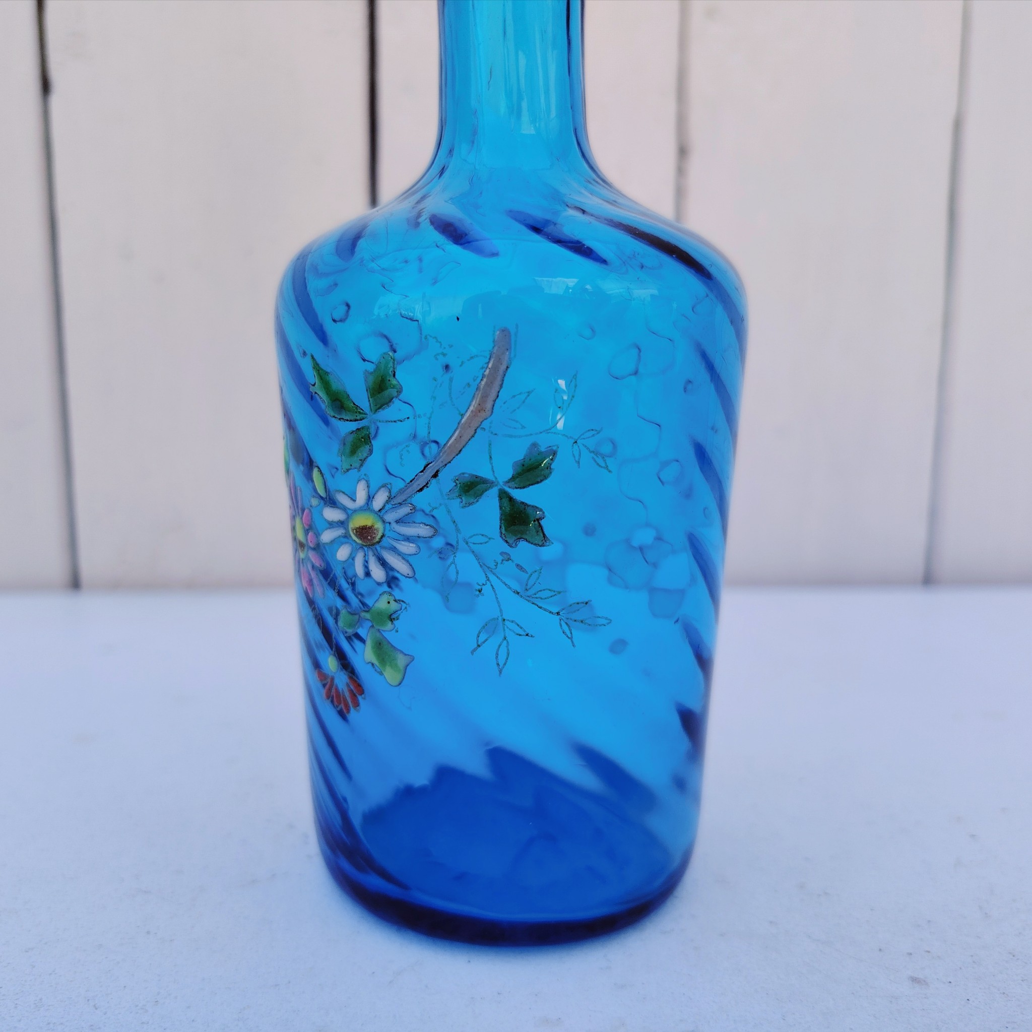 Ancienne bouteille en verre  torsadé de couleur bleu à décor frise florale émaillée Très bon état. Hauteur  : 17 cm