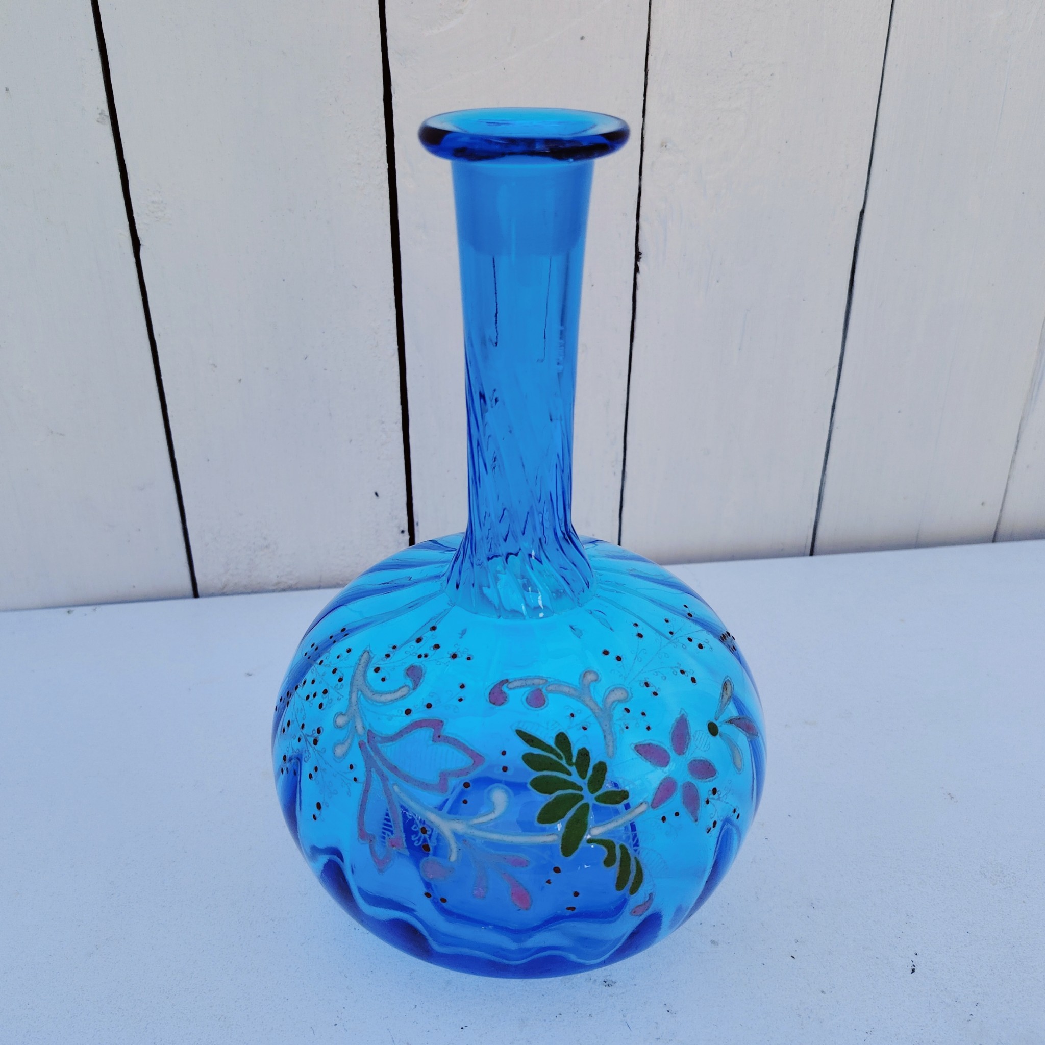 Ancienne carafe en verre effet torsadé de couleur bleu à décor frise florale émaillée Manque le bouchon Très bon état. Hauteur  : 23 cm