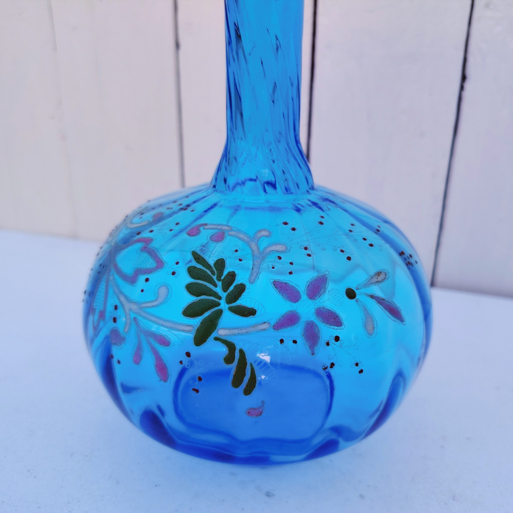 Ancienne carafe en verre effet torsadé de couleur bleu à décor frise florale émaillée Manque le bouchon Très bon état. Hauteur  : 23 cm