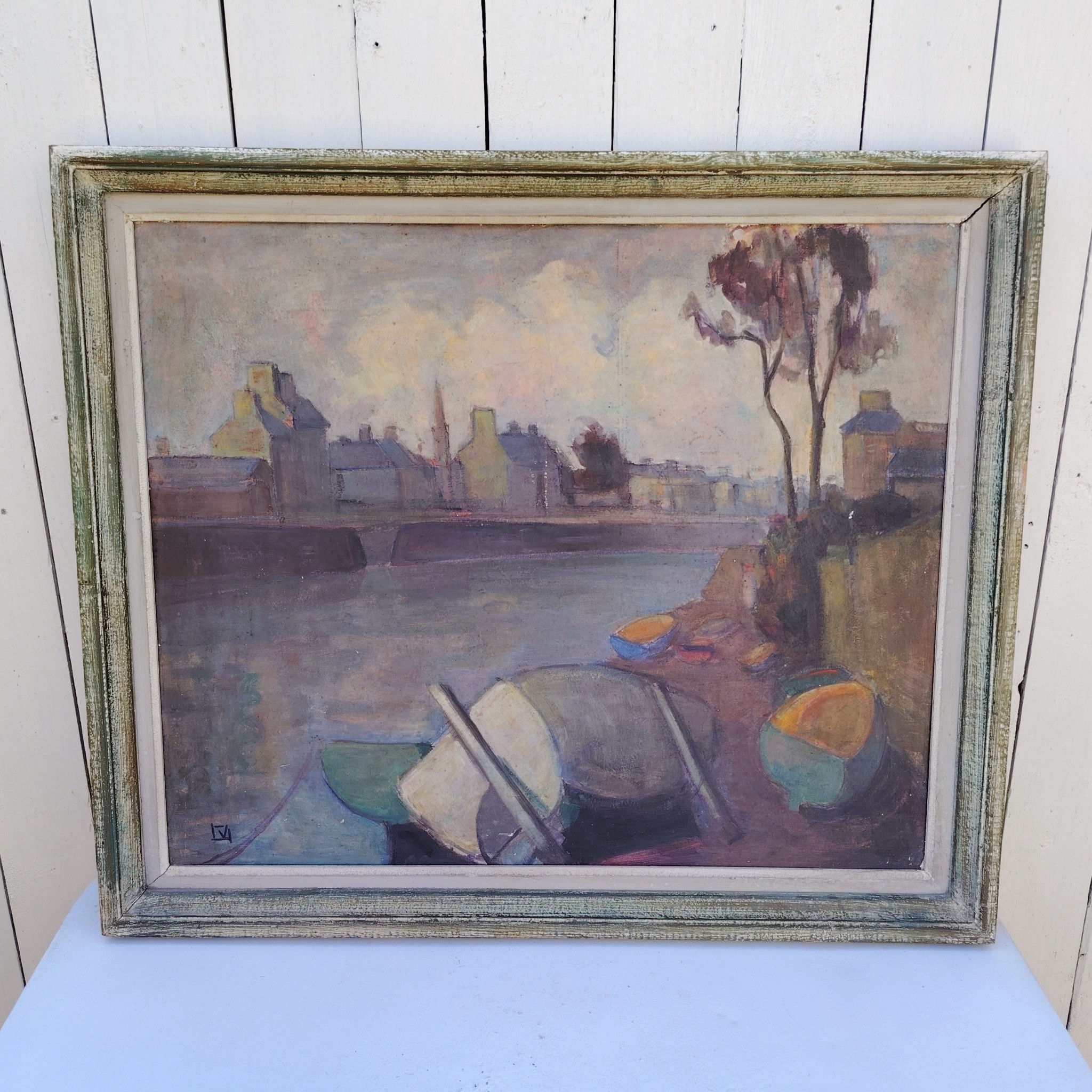 Grand tableau représentant un bord de rivière breton, au premier plan des barques en cale sèche, et au dernier la ville au bord de la rivière. Cadre en bois patiné vert. Une inscription sur le bas a gauche. Bon état général. Dimensions : 74 x 63 cm