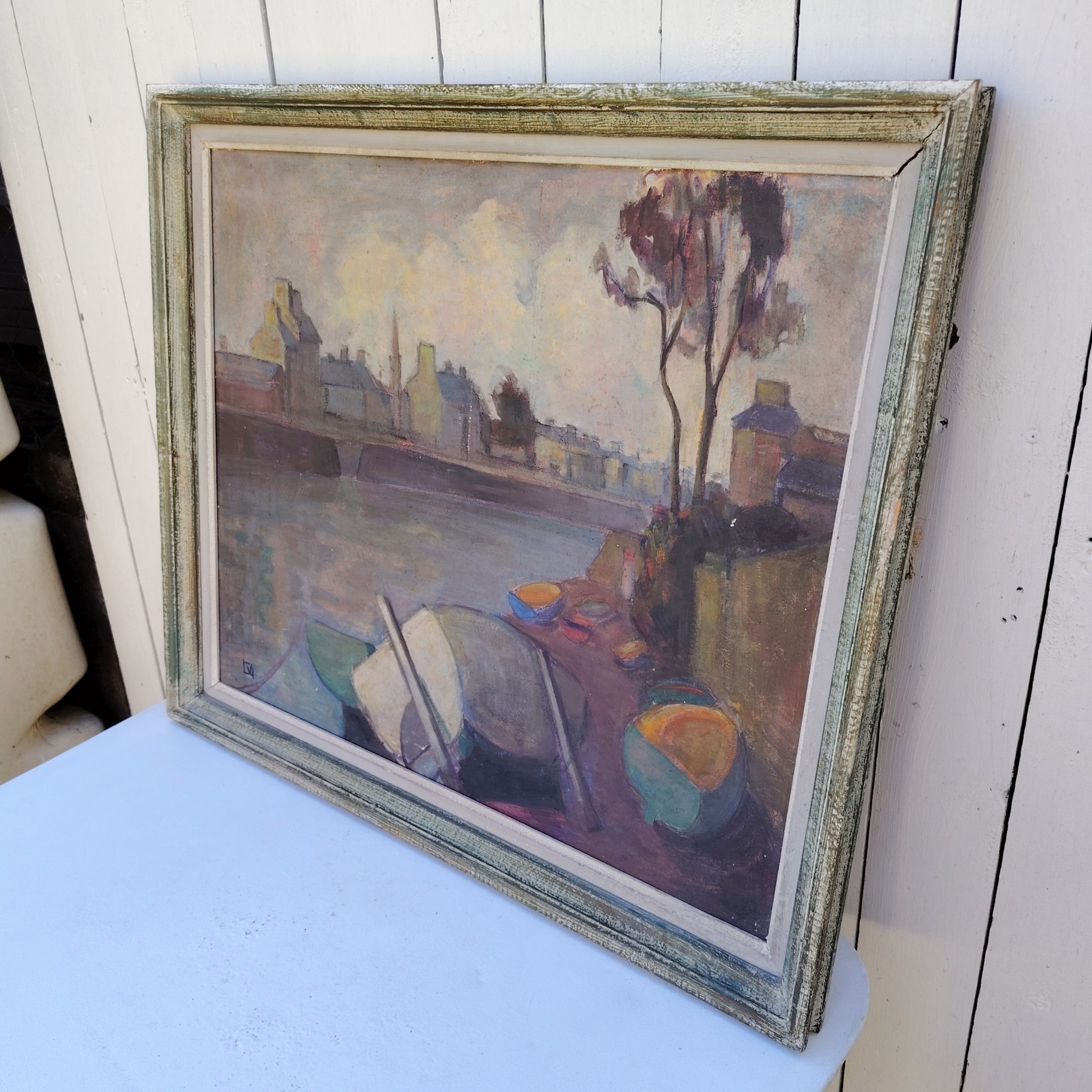 Grand tableau représentant un bord de rivière breton, au premier plan des barques en cale sèche, et au dernier la ville au bord de la rivière. Cadre en bois patiné vert. Une inscription sur le bas a gauche. Bon état général. Dimensions : 74 x 63 cm