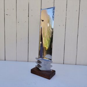 Aube de réacteur d'avion en métal poli miroir, fixée sur un socle un bois. Un numéro de série sur le bas K 3014. Décoration très moderne et design. Des petites rayures. Très bon état général Hauteur avec socle : 37 cm