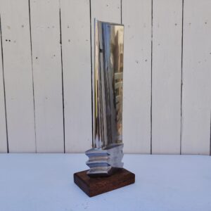 Aube de réacteur d'avion en métal poli miroir, fixée sur un socle un bois. Un numéro de série sur le bas K 3014. Décoration très moderne et design. Des petites rayures. Très bon état général Hauteur avec socle : 37 cm