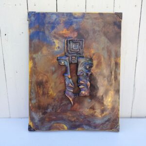Plaque en cuivre avec deux visages en reliefs au centre qui sont en métal patiné bronze, le tout collé sur un panneau de bois très épais. Signé en bas d'un visage. Bon état général. Dimensions : 38,5 x 30 cm