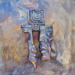 Plaque en cuivre avec deux visages en reliefs au centre qui sont en métal patiné bronze, le tout collé sur un panneau de bois très épais. Signé en bas d'un visage. Bon état général. Dimensions : 38,5 x 30 cm