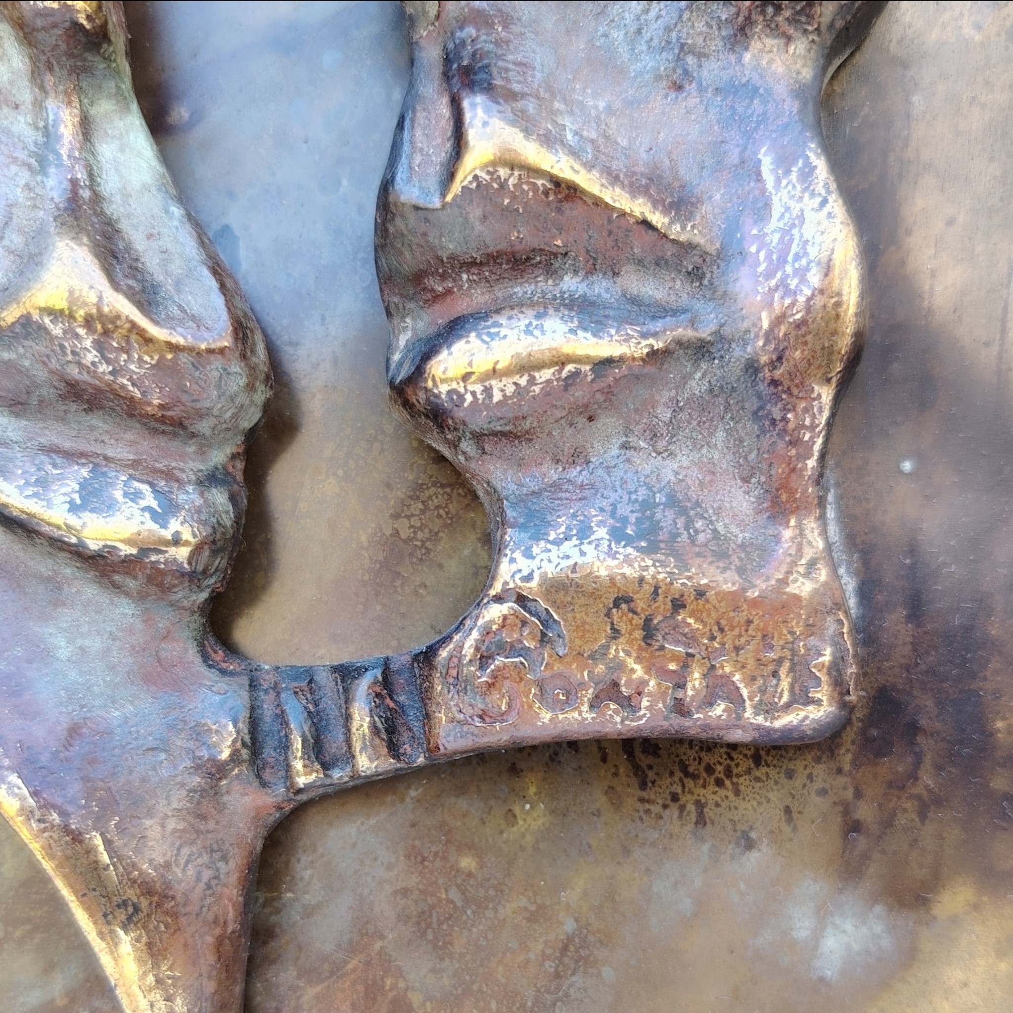 Plaque en cuivre avec deux visages en reliefs au centre qui sont en métal patiné bronze, le tout collé sur un panneau de bois très épais. Signé en bas d'un visage. Bon état général. Dimensions : 38,5 x 30 cm