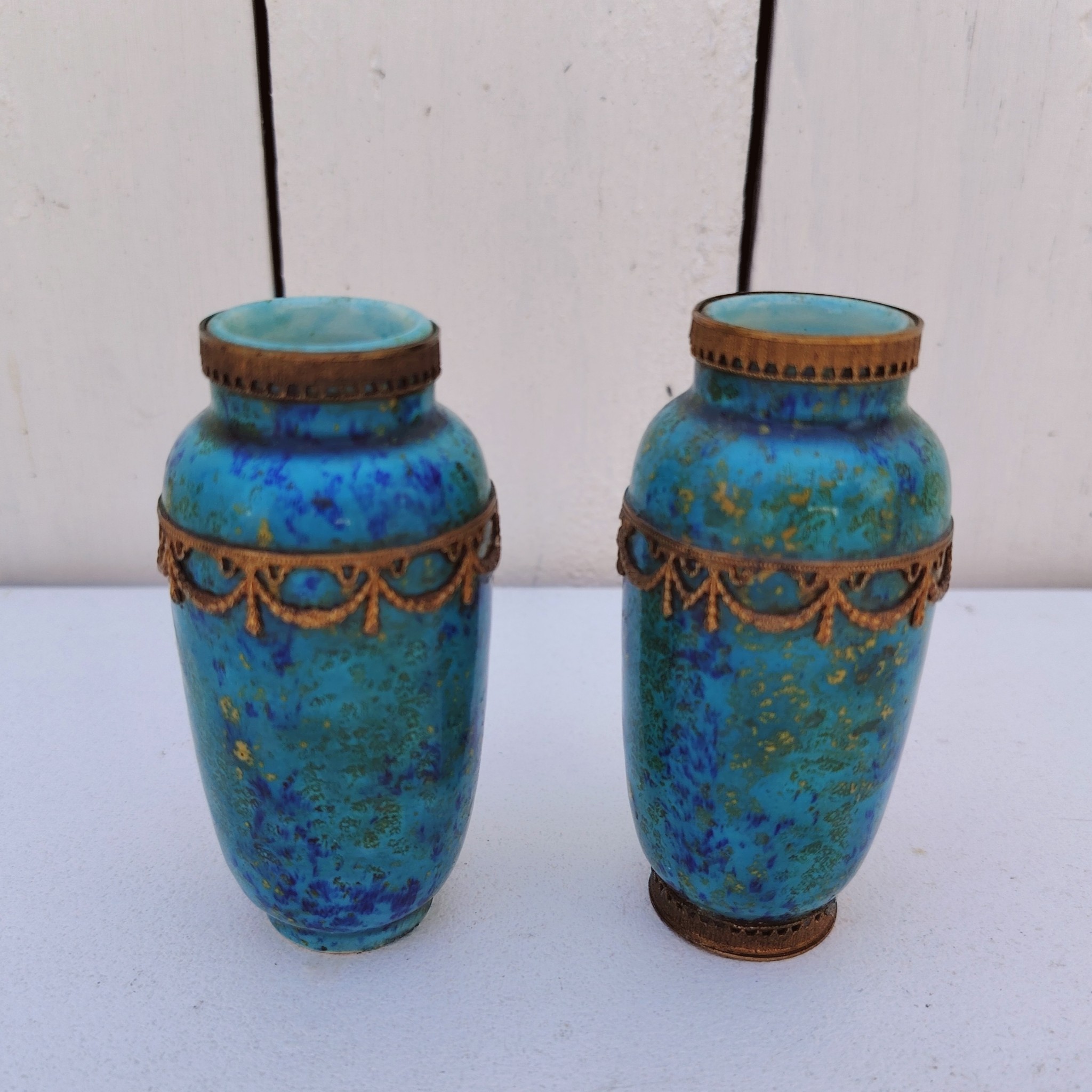Paires de vases miniatures art déco attribués à Paul Millet, en céramique de sèvres. Dans les tons bleus avec des touches de doré. Un cachet sur le dessous.  Manque le cerclage bronze au pied d'un vase. Bon état général. Hauteur : 8,5 cm