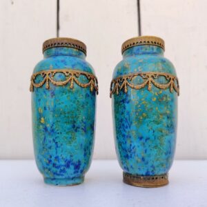 Paires de vases miniatures art déco attribués à Paul Millet, en céramique de sèvres. Dans les tons bleus avec des touches de doré. Un cachet sur le dessous.  Manque le cerclage bronze au pied d'un vase. Bon état général. Hauteur : 8,5 cm