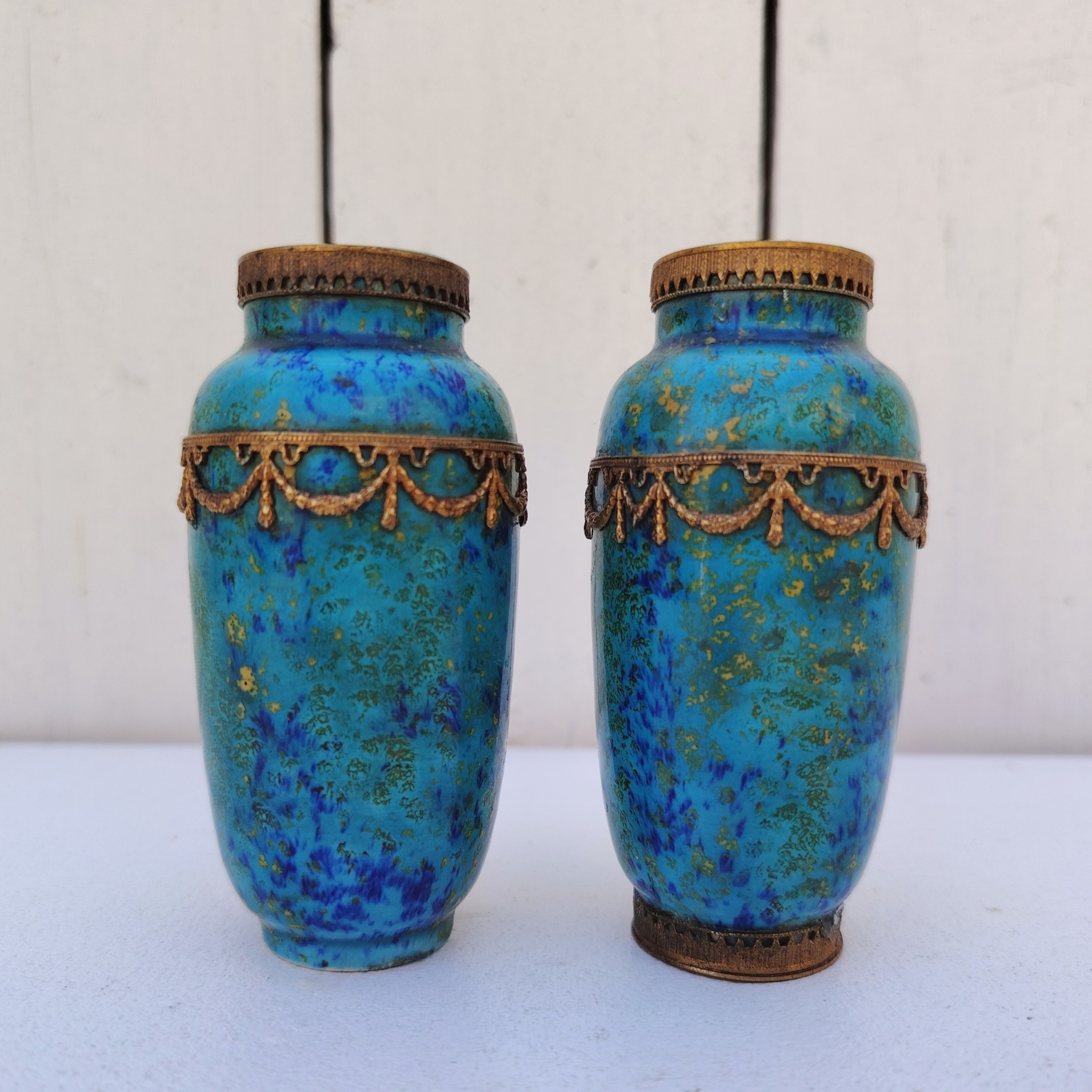 Paires de vases miniatures art déco attribués à Paul Millet, en céramique de sèvres. Dans les tons bleus avec des touches de doré. Un cachet sur le dessous.  Manque le cerclage bronze au pied d'un vase. Bon état général. Hauteur : 8,5 cm