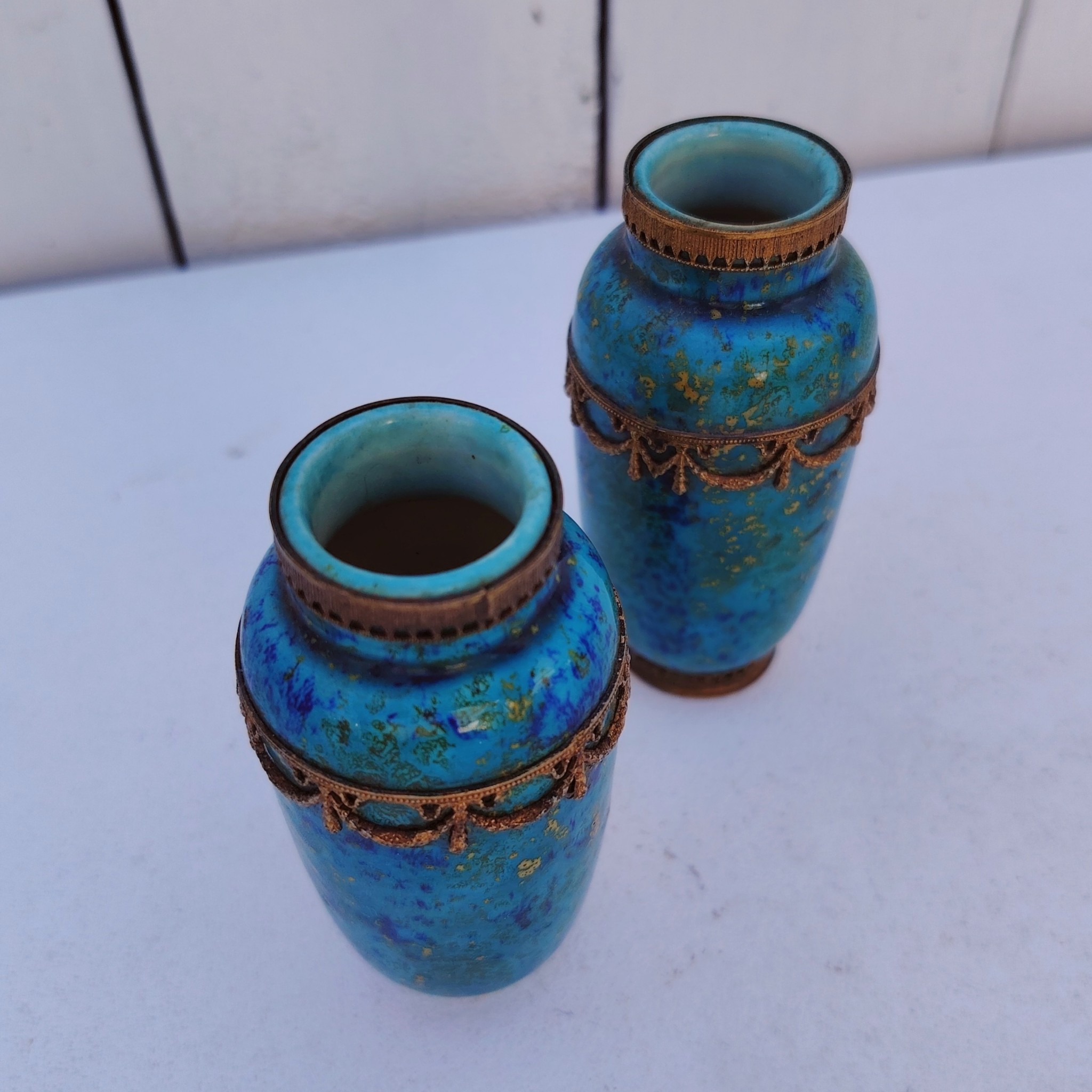 Paires de vases miniatures art déco attribués à Paul Millet, en céramique de sèvres. Dans les tons bleus avec des touches de doré. Un cachet sur le dessous.  Manque le cerclage bronze au pied d'un vase. Bon état général. Hauteur : 8,5 cm