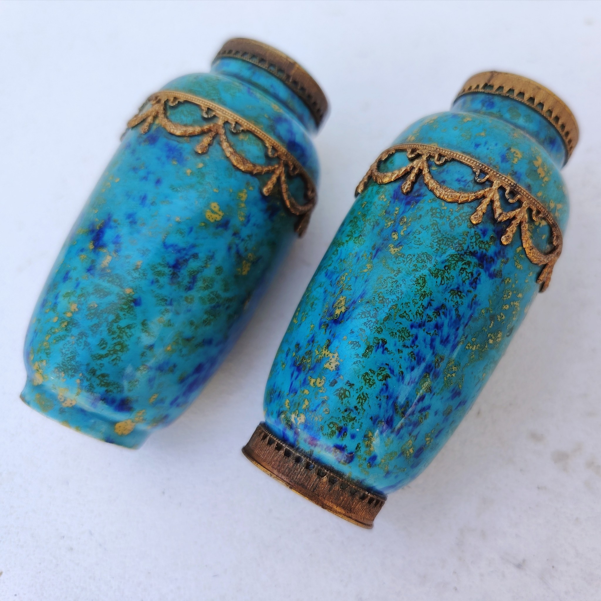 Paires de vases miniatures art déco attribués à Paul Millet, en céramique de sèvres. Dans les tons bleus avec des touches de doré. Un cachet sur le dessous.  Manque le cerclage bronze au pied d'un vase. Bon état général. Hauteur : 8,5 cm