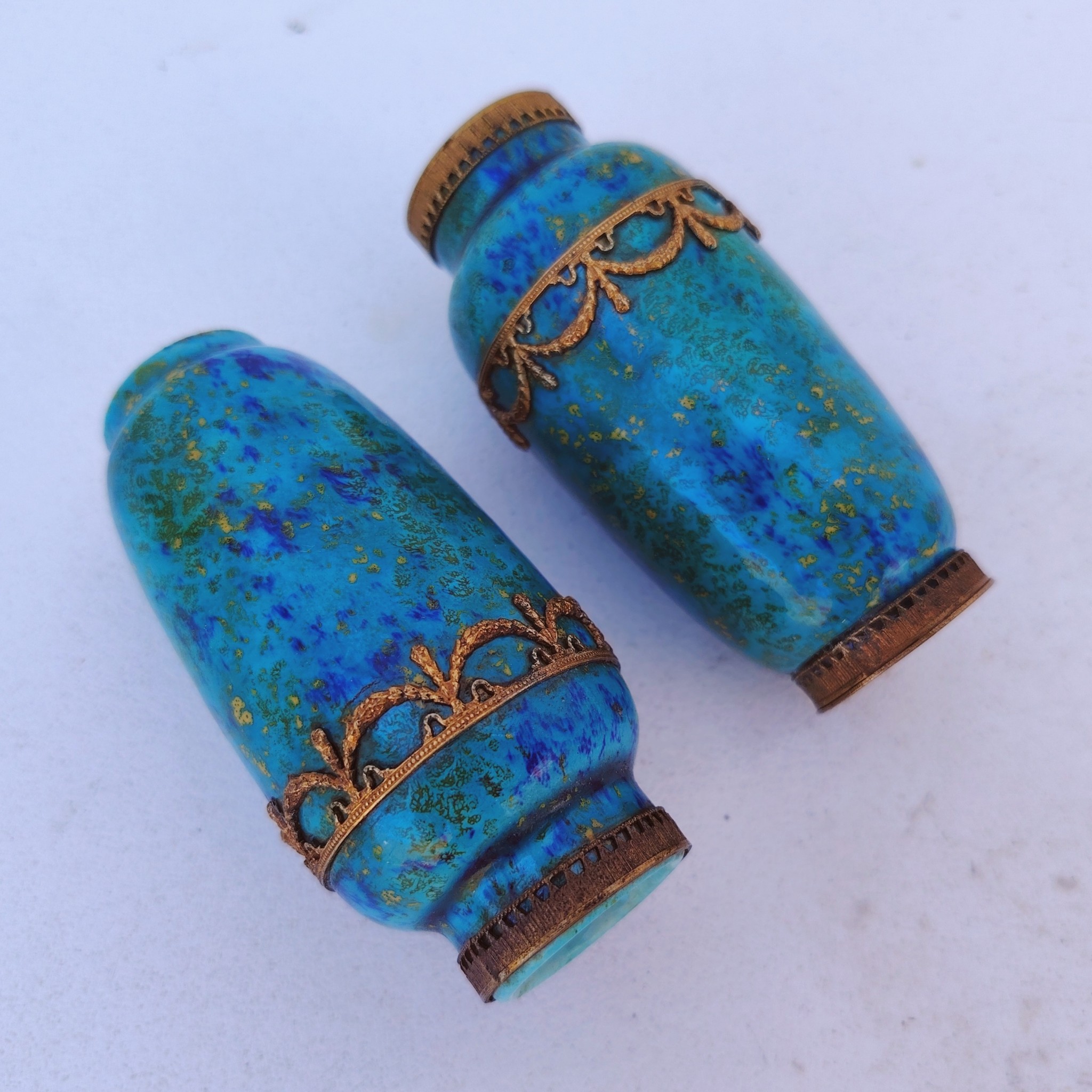 Paires de vases miniatures art déco attribués à Paul Millet, en céramique de sèvres. Dans les tons bleus avec des touches de doré. Un cachet sur le dessous.  Manque le cerclage bronze au pied d'un vase. Bon état général. Hauteur : 8,5 cm