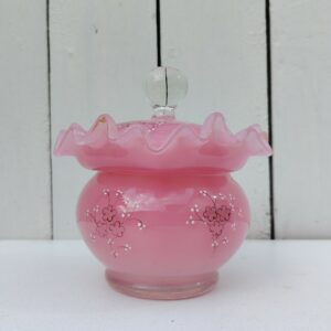 Pot couvert pouvant servir de baguier ou autre en verre soufflé de couleur rose, collerette torsadée. Décor de fleur rehaussé de points émaillés blancs en relief. Les fleurs et la prise du couvercle devait être certainement doré car on y voit encore le petites de la dorure. Un petit éclat sur l'intérieur du couvercle non visible quand il est fermé, et traces blanches sur le talon du pot non visible quand il est posé. Bon état général Hauteur avec couvercle : 13 cm Diamètre : 11 cm
