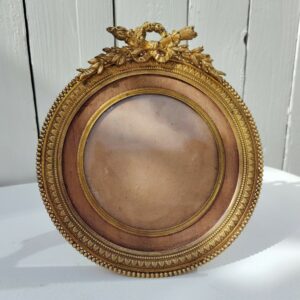 Grand cadre photo chevalet en bronze doré et bois, style Louis XVI, noeud ruban sur le haut.  Une estampille sur l'arrière Bon état général Diamètre : 15,5 cm