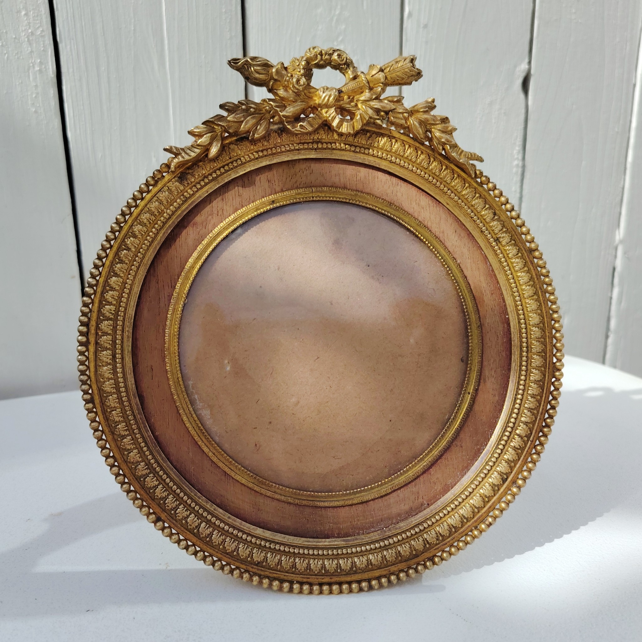 Grand cadre photo chevalet en bronze doré et bois, style Louis XVI, noeud ruban sur le haut.  Une estampille sur l'arrière Bon état général Diamètre : 15,5 cm