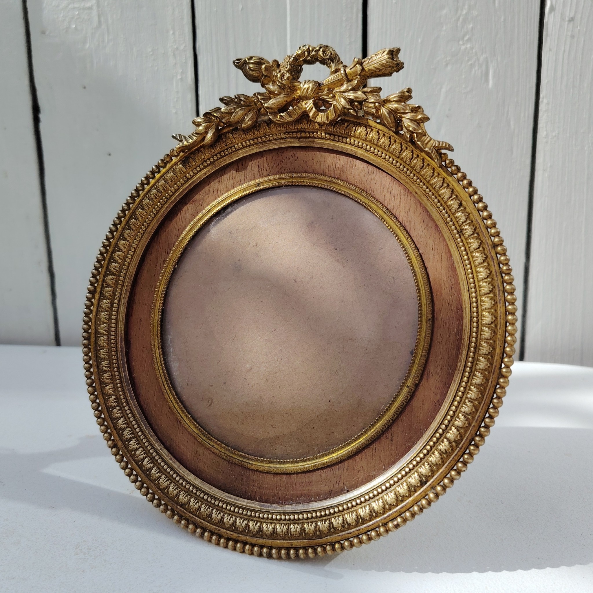 Grand cadre photo chevalet en bronze doré et bois, style Louis XVI, noeud ruban sur le haut.  Une estampille sur l'arrière Bon état général Diamètre : 15,5 cm