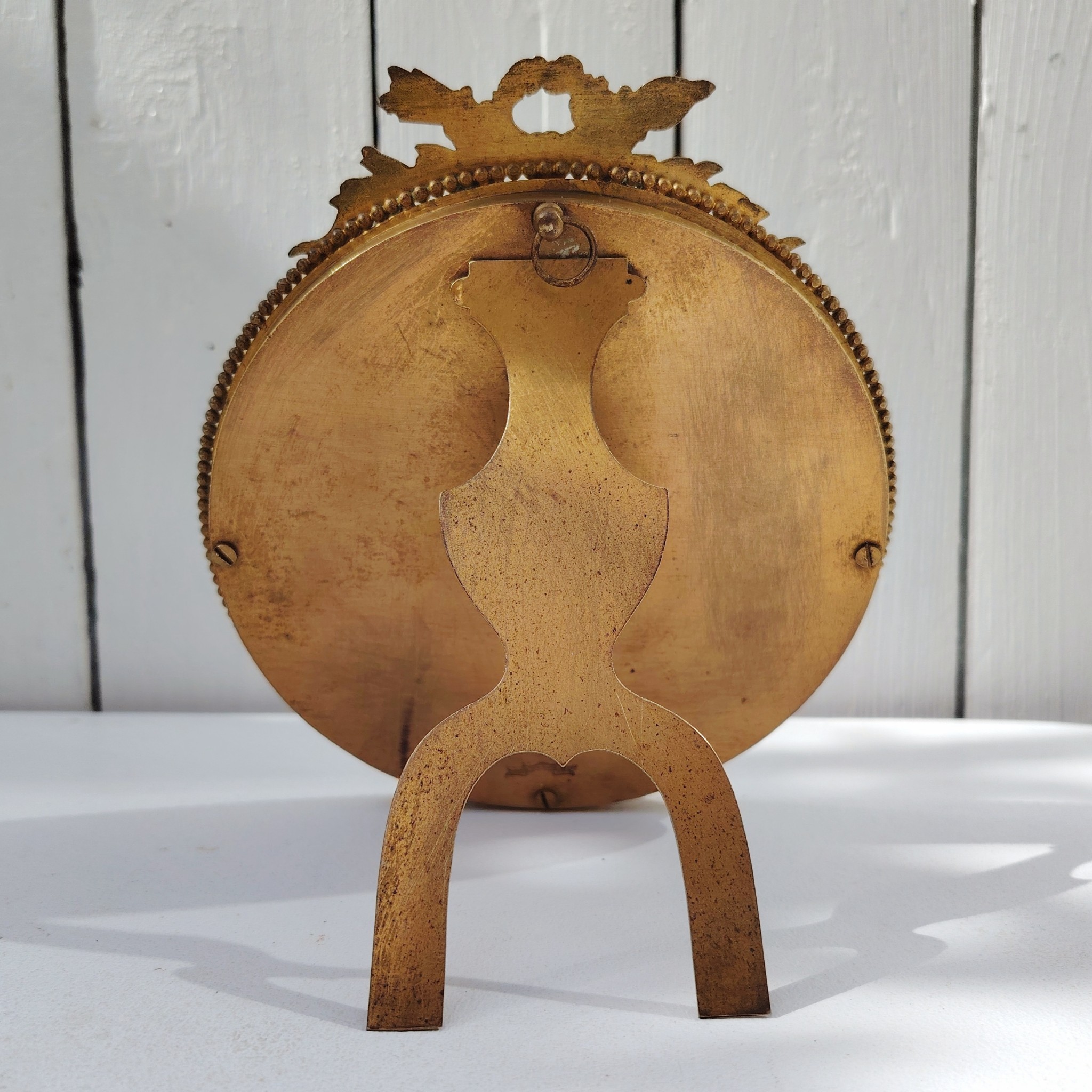 Grand cadre photo chevalet en bronze doré et bois, style Louis XVI, noeud ruban sur le haut.  Une estampille sur l'arrière Bon état général Diamètre : 15,5 cm