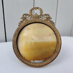 Cadre photo chevalet en bronze doré, style Louis XVI, Ruban sur le haut. Une trace de photo collée sur le rebord intérieur. Bon état général Diamètre : 9 cm