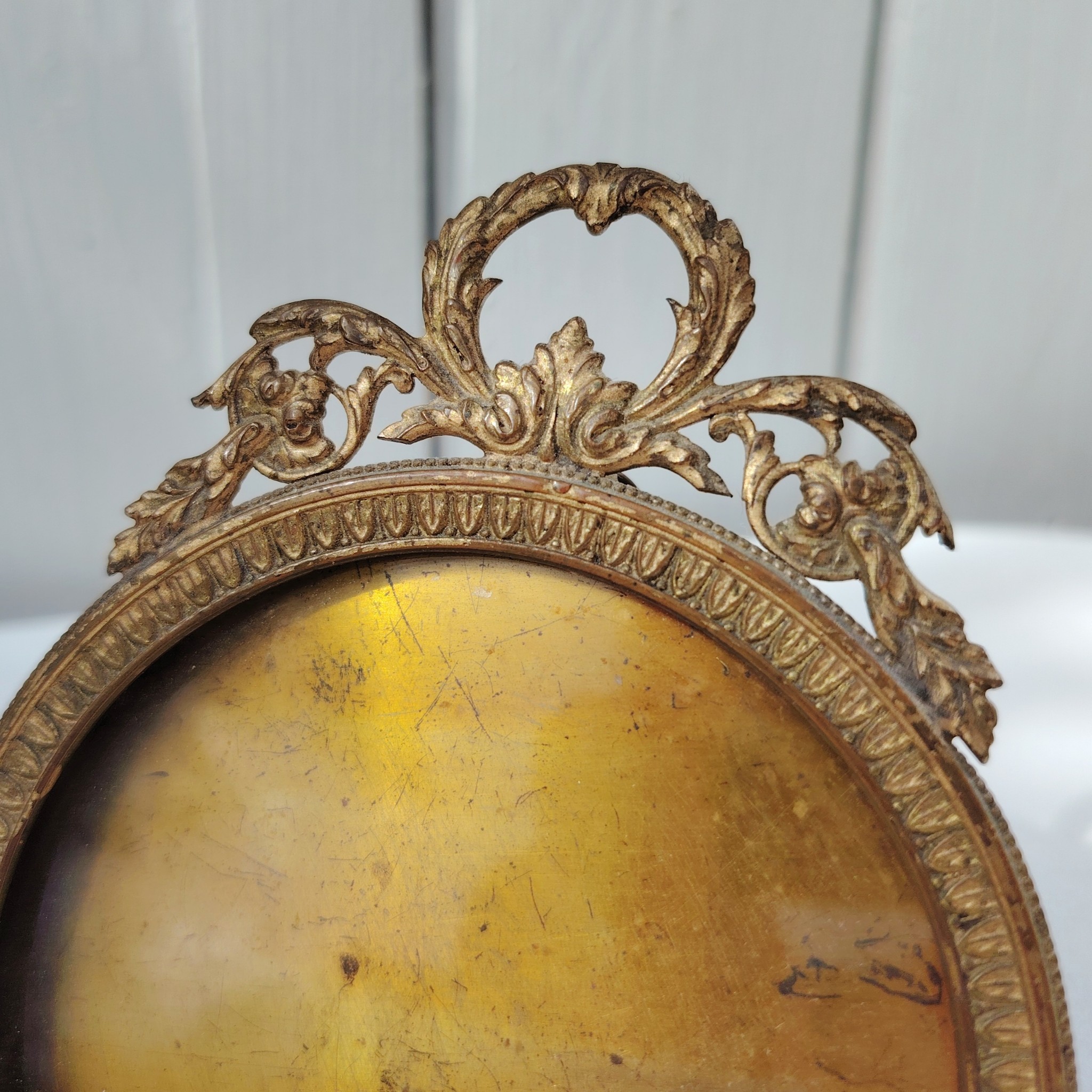 Cadre photo chevalet en bronze doré, style Louis XVI, Ruban sur le haut. Une trace de photo collée sur le rebord intérieur. Bon état général Diamètre : 9 cm