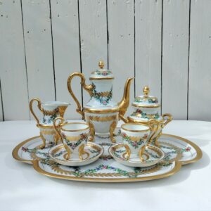 Service à café tête à tête en porcelaine de Limoges, comprenant le plateau, la cafetière, les deux tasses avec soucoupes, le pot à lait et le sucrier. Décor floral orné de dorure. Estampillé Porcelaine de limoge avec les initiales du décorateur sous le plateau . Excellent état . Dimensions : Hauteur cafetière : 20,5 cm Hauteur sucrier avec couvercle : 14 cm Hauteur pot à lait : 11,5 cm Hauteur tasse : 8,5 cm diamètre tasse : 5,7 cm diamètre soucoupe : 11,5  Dimensions plateau : 40,5 x 30,5 cm