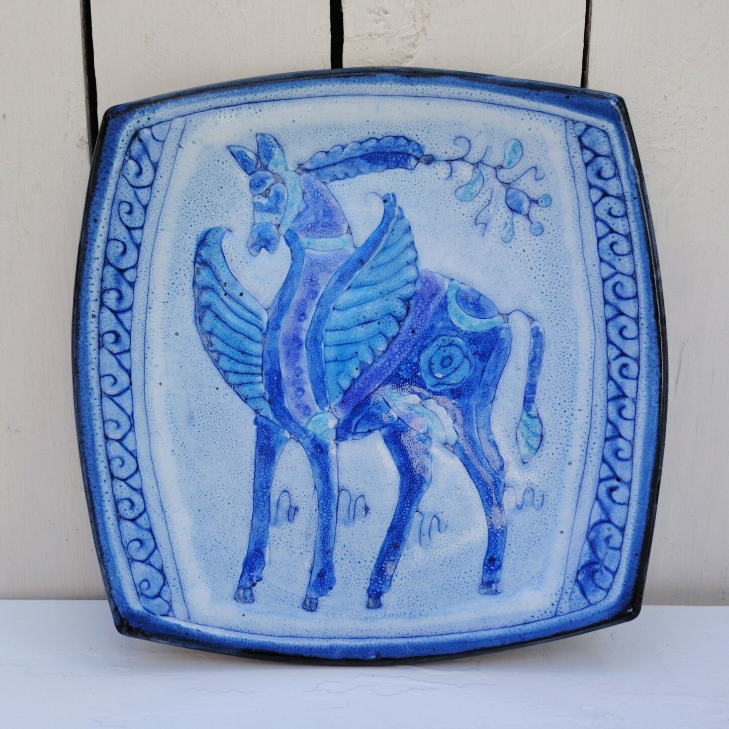 assiette en céramique, créée par Danuta le Henaff. Signée sur le dessous avec son étiquette d'origine. Décor d'un cheval ailé  Très bon état. Dimensions : 23 x 22,5 cm