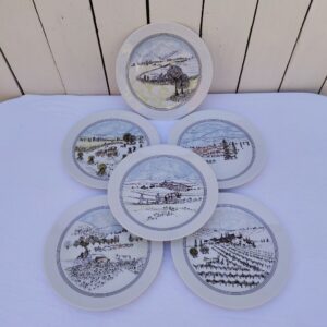 Six assiettes à dessert en porcelaine d'Auteuil, paysages naïf, décor créé par Danielle Dillemann. Six décors différents, légères traces d'usage. Très bon état. Diamètre : 19 cm