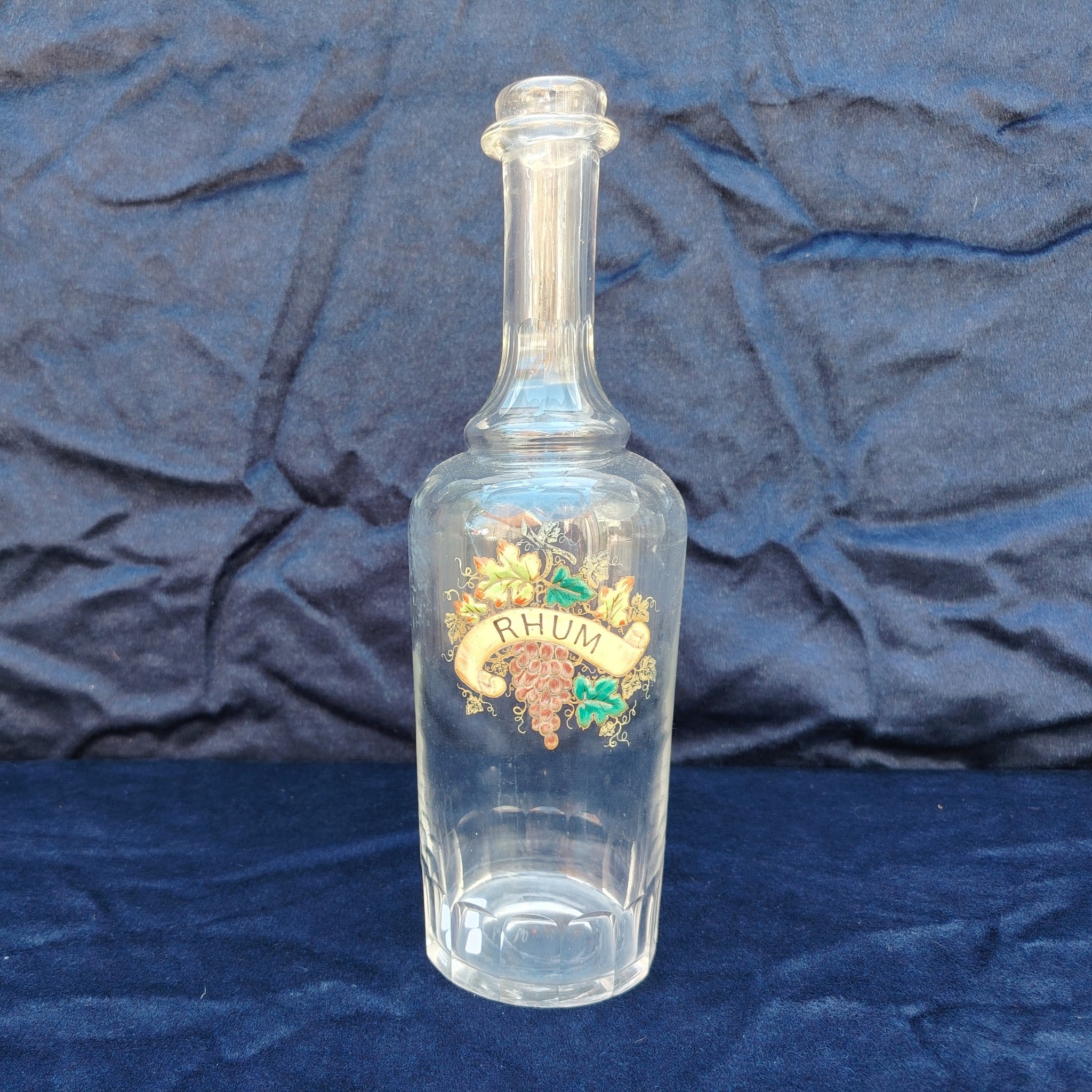 Ancienne bouteille en verre taillé à facette, décor émaillé en relief, marqué Rhum. (Idéale pour faire son rhum arrangé) Des petites traces de calcaire et traces d'usage. Bon état général Hauteur : 30 cm