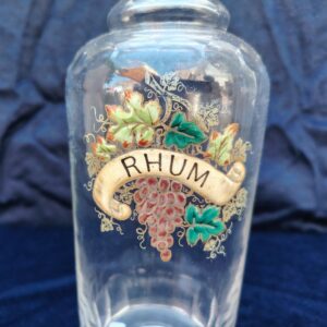 Ancienne bouteille en verre taillé à facette, décor émaillé en relief, marqué Rhum. (Idéale pour faire son rhum arrangé) Des petites traces de calcaire et traces d'usage. Bon état général Hauteur : 30 cm