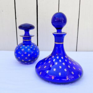 Flacons en verre bleu cobalt, de style Napoléon III, datant de la fin du XIX ème début XX ème, à décor d'étoiles dorées. Traces d'usures blanches sur le dessous des flacons , non visible une fois posés Bon état général Hauteurs avec bouchon : 16, et 13 cm Diamètre : 12 et 6,5 cm
