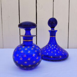 Flacons en verre bleu cobalt, de style Napoléon III, datant de la fin du XIX ème début XX ème, à décor d'étoiles dorées. Traces d'usures blanches sur le dessous des flacons , non visible une fois posés Bon état général Hauteurs avec bouchon : 16, et 13 cm Diamètre : 12 et 6,5 cm