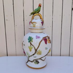 Grand pot couvert en porcelaine portugaise Pac. Orné de vignes et grappes de raisins en relief, et de papillons et coccinelles peints. Liseré doré, poignée du couvercle représentant une branche dorée surhaussé d'un perroquet. Très belle facture. Excellent état.  Hauteur avec couvercle : ~47 cm
