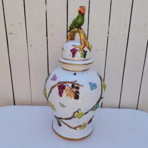 Grand pot couvert en porcelaine portugaise Pac. Orné de vignes et grappes de raisins en relief, et de papillons et coccinelles peints. Liseré doré, poignée du couvercle représentant une branche dorée surhaussé d'un perroquet. Très belle facture. Excellent état.  Hauteur avec couvercle : ~47 cm